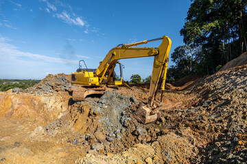Obraz premium an excavator vehicle is working digging the ground with a tropical forest in the background