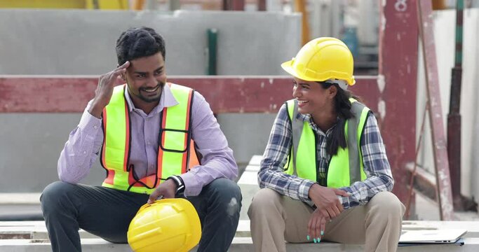 Happy worker enjoying free time. Asian indian man and woman warehouse worker sitting on workshop site break relax time at precast factory.