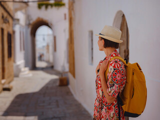 Nice asian Female in boho dress Enjoying Sunny Day on Greek Islands. Travel to Lindos, Mediterranean islands tourist season. Tourist woman on vacation in Greece walking through the streets of Lindos.