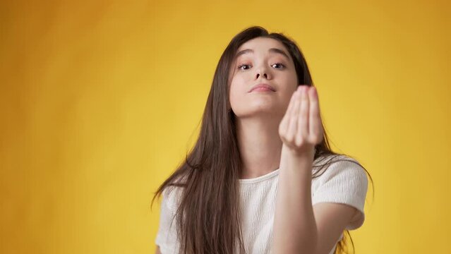 Stressed out looking casually dressed young woman with long dark hair making distressing signs with both hands apparently being agitated against amber background