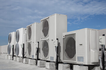 Air conditioning (HVAC) on the roof of an industrial building with blue sky and clouds.	