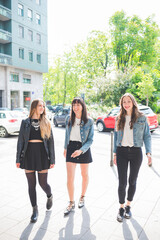 Three young happy women friends walking outdoors having fun