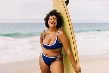 Happy plus size woman enjoying surfing adventure at the beach