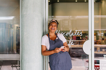 Successful female entrepreneur smiling and using smartphone in café