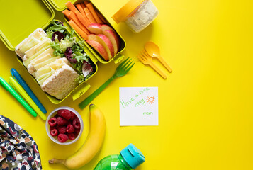 School lunch box with sandwiches, carrot sticks, apple, banana, lettuce, hummus and raspberries....