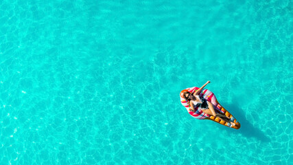 Relaxed girl on an inflatable mattress in the pool in the summer relaxes and swims, shot from above by a drone