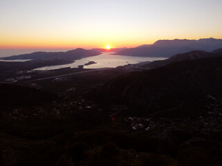 Aerial drone view of beautiful sunset or sunrise landscape with clear sky in the Bay of Kotor, Adriatic sea, Montenegro. Tranquil skyline with bright orange sunlight. Summer holiday concept