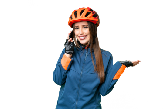 Young cyclist woman over isolated chroma key background keeping a conversation with the mobile phone with someone