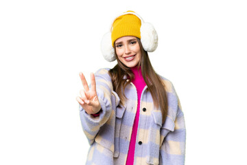 Young woman wearing winter muffs over isolated chroma key background smiling and showing victory sign