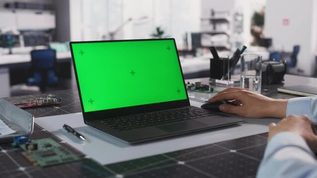 Anonymous Engineer Working in Lab on a Laptop Computer with Mock Up Green Screen Chromakey Display with Motion Tracker Placeholders. Video Template for Industrial Content Creation and Presentation