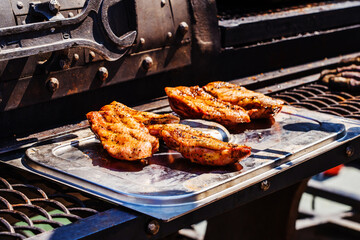 Grilled chicken breasts lie on a metal tray against the background of the barbecue. Foreground. selective focus