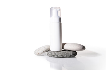 Facial foam in a bottle on sea rocks, skin cleansing bottle