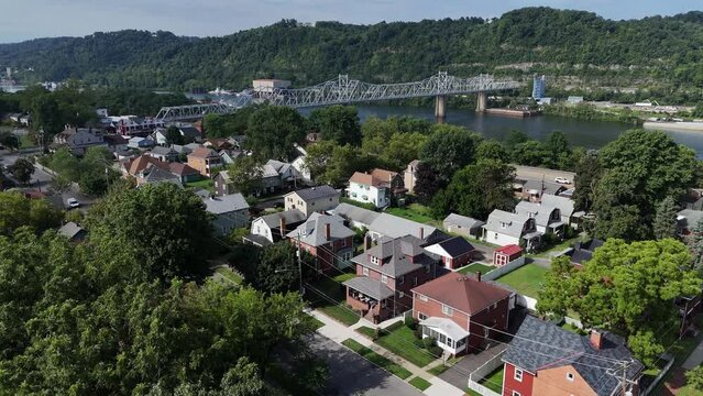 A slow forward aerial establishing shot view of a small Pennsylvania river town. Bridge over the Ohio River in the distance. Pittsburgh suburbs.  	