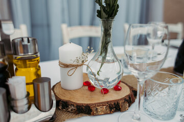 Served table at the wedding. Transparent vase on the table with wildflowers. Decorated with white candles. Glasses and glasses for drinks. Wedding table setting.