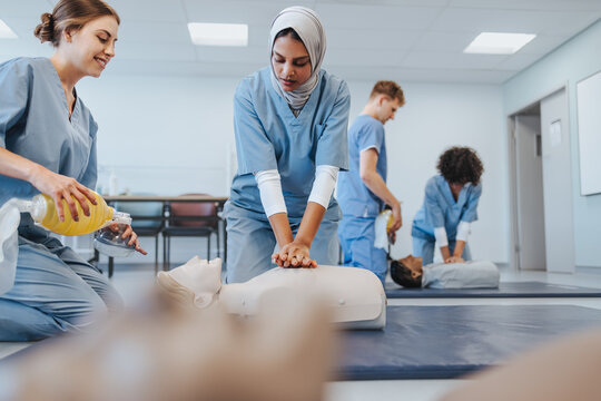 Female medical students in scrubs practice CPR on a manikin in clinical simulation centre