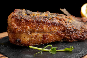 Fried fish on black slate on a wooden board on a dark background. Flounder