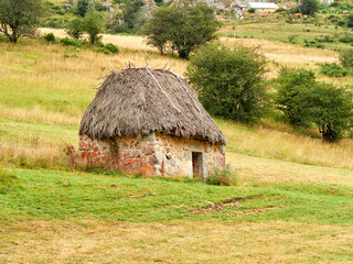 Fototapeta na wymiar Typical Asturian house called teito. Green roof and stone walls, with a square or rectangular plan. Cattle house.