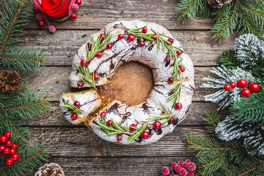 Traditional homemade christmas cake holiday dessert with cranberry and chocolate with new year tree decoration on vintage wooden table background. Rustic style.
