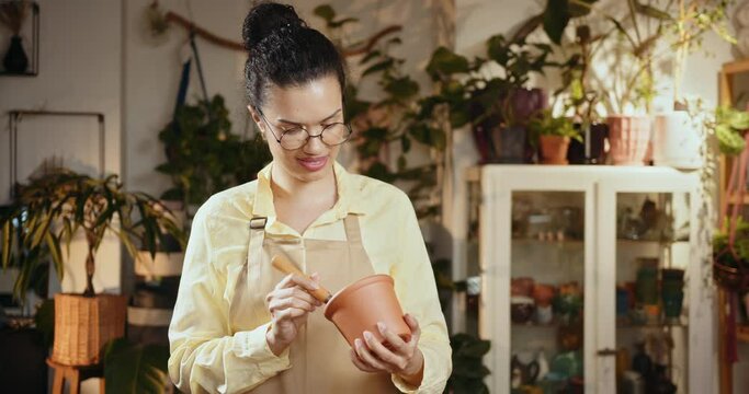 Small business entrepreneur and plant caring concept. A black woman transplants a houseplant, a flower in a ceramic pot