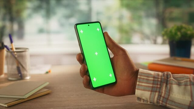 Anonymous Man Holding a Smartphone Device, Reading Articles on Mobile Phone with Green Screen Mock Up Display. Video Template with Placeholder for Digital Marketing and Business Promotions