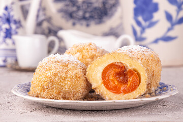 Austrian and czech sweet dessert knedle apricot dumplings against white blue antick vintage dishes. Filled cottage cheese dough.