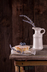 Muffin with bluberry decorated with lavender on rustic old wooden bench against of dark background