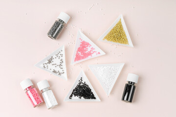 Different colored seed beads in containers for needlework and beading. Triangular bead trays on...