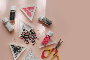 Triangular bead trays with beaded earrings. Different colored seed beads in containers for needlework and beading. Creativity and  hobby concept