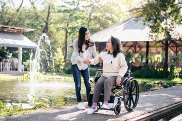 Senior on wheelchair and daughter family concept, Young asian woman helping disabled mother to get up