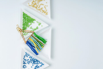 Triangular bead trays with beaded earrings. Different colored seed beads in containers for needlework and beading. Creativity and  hobby concept