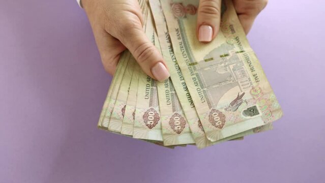 Woman counting AED dirhams in hands, closeup