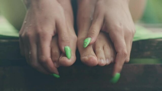 girl doing foot massage with her hands with green nails