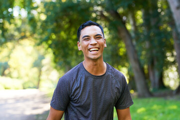 Fototapeta na wymiar Attractive Asian man laughing on trail run, walking in nature beautiful scenery