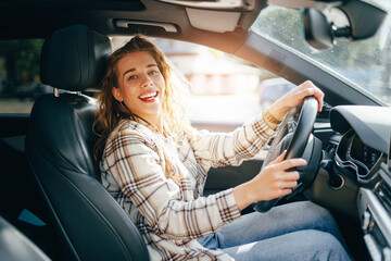 Happy smiling woman inside a car driving in the street