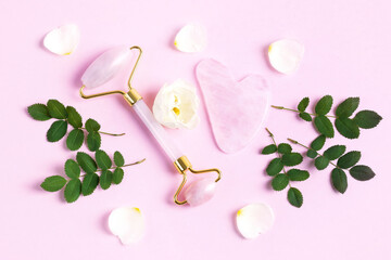 Modern selfcare concept. Pink jade roller and gua sha for face massage with flowers roses. Facial massager tools. Anti age, lifting and toning care.