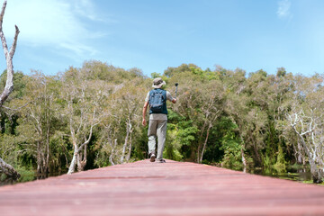 Fototapeta premium Asian man taking a walk on a bridge river and mangrove forest