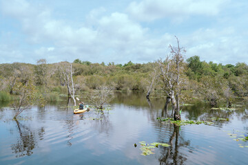 Asian man rowing a boat on a river in the Asian jungle, morning, fun, travel alone