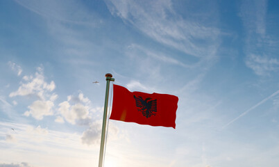 Flag of Albania flag waving in the wind, sky and sun background. Albania Flag.