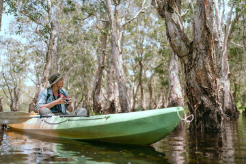 Asian man rowing a boat on a river in the Asian forest Taking pictures in the mangrove forest