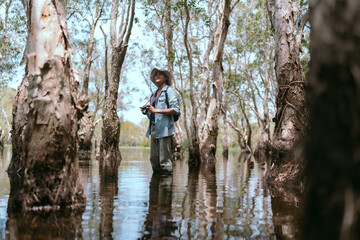 Asian man traveling hiking taking photos alone in the Asian mangrove forests.
