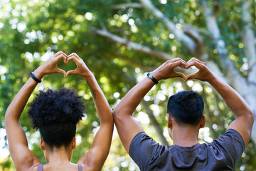 Back view of man and woman holding up heart shape with hands, fitness theme