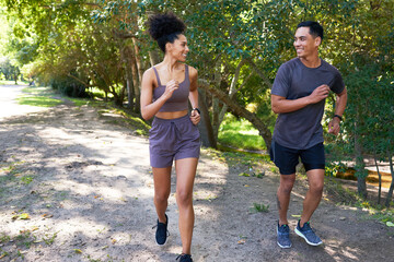 Fit couple runs together in park, trail running outdoors smiling and happy