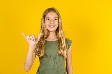 blonde kid girl wearing green T-shirt over yellow studio background showing up number six Liu with...
