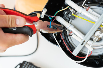 Repair of small household appliances, pliers in the hands of the master. Home repair service. Repair shop.