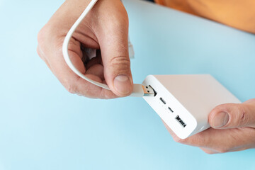 Charging a power bank, a man connects the cable to the cell.