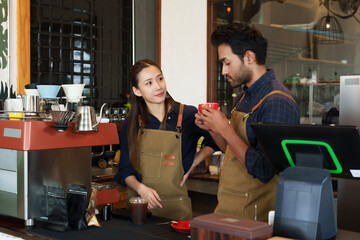 Store owner, politely dressed Asian man wearing apron in front, prepares for opening cafe, was drinking hot coffee from small cup, which wife barista made test craft, raised hand praised wife.