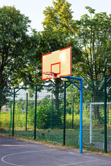 Empty basketball court on a sunny day. Basketball ring and court on the background of nature.