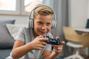 Young Caucasian boy enjoys playing video games with joystick.