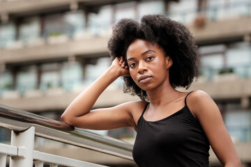 Curly black model leaning on banister.