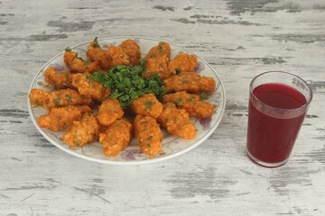 Potato dumplings in white plate with cold red drink on table. Sitting view. Vegan and healthy food concept idea. Potato dumpling known as 'patatesli bulgur kofte' in Hatay, Turkiye.
